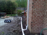 Drains being installed with 4'' PVC pipe. This allows for great drainage, that should never clog. Notice how the downspout is relatively sealed where it is connected to the pipe.